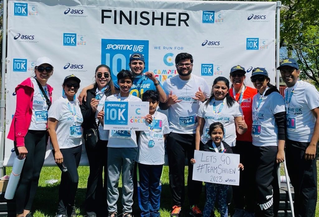 Team Shiven runners holding a Lets go #TeamShiven 2023 sign at the Sporting Life 10K finish line